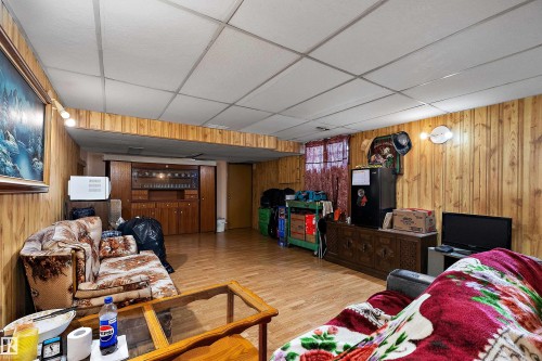 Recreation room featuring wood paneling, wood-finish flooring, and a drop ceiling - 15907 101 Street, Edmonton, AB - Indoor