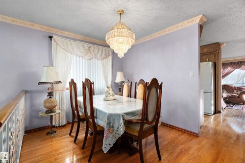Dining space featuring wood-finish flooring, a crystal chandelier, and crown molding - 15907 101 Street, Edmonton, AB - Indoor Photo Showing Dining Room