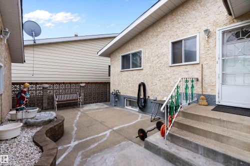 Concrete patio with a decorative privacy screen, stucco exterior, and concrete steps with a metal handrail - 15907 101 Street, Edmonton, AB - Outdoor With Exterior
