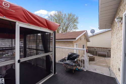 Outdoor deck space featuring dark-finish flooring, white railing, and an attached screened enclosure with a red canopy - 15907 101 Street, Edmonton, AB - Outdoor With Exterior