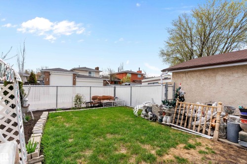 Expansive backyard featuring a green lawn, white chain-link fencing, and a stucco-finished outbuilding with a brown shingle roof - 15907 101 Street, Edmonton, AB - Outdoor