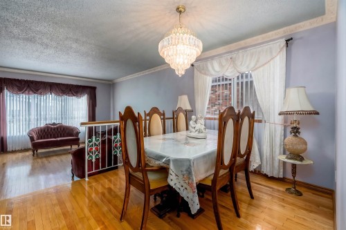Dining area featuring a tiered chandelier, hardwood flooring, and light blue wall paint - 15907 101 Street, Edmonton, AB - Indoor Photo Showing Dining Room