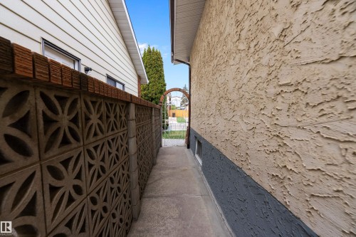 Stucco exterior with a contrasting lower foundation, complemented by a decorative block fence with a brick cap - 15907 101 Street, Edmonton, AB - Outdoor