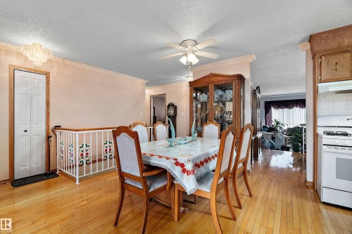 Open-concept dining area with wood-finish flooring, a crystal chandelier, and a ceiling fan - 15907 101 Street, Edmonton, AB - Indoor Photo Showing Dining Room