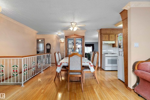 Open-concept living space featuring wood-finish flooring, crown molding, and a decorative staircase railing - 15907 101 Street, Edmonton, AB - Indoor Photo Showing Dining Room