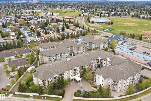 Multi-story residential complex featuring multiple balconies, a covered entry, and surrounding mature trees - 124 10511 42 Avenue, Edmonton, AB 