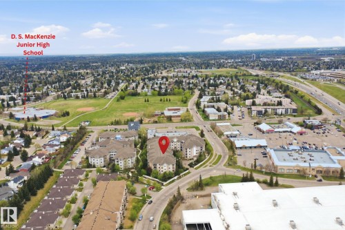 Aerial depiction of a residential and commercial area featuring multi-story buildings, established tree cover, and a visible major roadway - 124 10511 42 Avenue, Edmonton, AB 