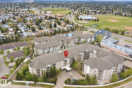 Multi-story residential complex featuring multiple buildings with private balconies and a central entrance canopy - 124 10511 42 Avenue, Edmonton, AB 