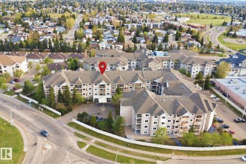 Multi-story condominium complex featuring a light-toned facade, multiple private balconies, and a central covered entrance - 124 10511 42 Avenue, Edmonton, AB 