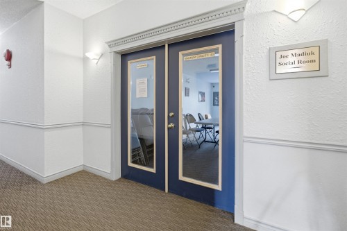 Double navy-blue glass-paneled doors with decorative molding frame the entrance to a social room - 124 10511 42 Avenue, Edmonton, AB 