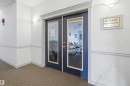 Double navy-blue glass-paneled doors with decorative molding frame the entrance to a social room - 124 10511 42 Avenue, Edmonton, AB 