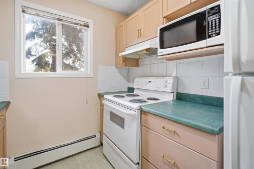 Kitchen featuring a white electric range, over-the-range microwave, and white refrigerator - 124 10511 42 Avenue, Edmonton, AB 