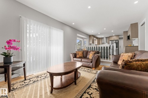 Open-concept living area featuring wood-finish flooring, recessed lighting, and a modern kitchen with stainless steel appliances and light wood-tone cabinetry - 10673 161 Avenue, Edmonton, AB - Indoor Photo Showing Living Room