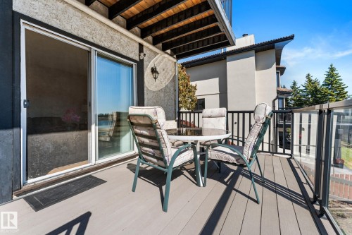Exterior balcony featuring composite decking, clear glass railing panels, black aluminum railings, and a sliding glass patio door - 10673 161 Avenue, Edmonton, AB - Outdoor With Exterior