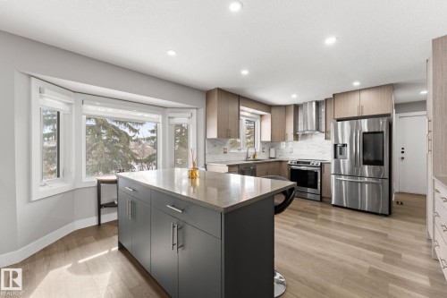 Contemporary kitchen featuring a bay window, light wood-finish flooring, stainless steel appliances, a center island with seating, and recessed lighting - 10673 161 Avenue, Edmonton, AB - Indoor Photo Showing Kitchen