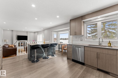 Modern kitchen featuring light wood-finish cabinetry, stainless steel appliances, and a grey kitchen island with seating - 10673 161 Avenue, Edmonton, AB - Indoor Photo Showing Kitchen