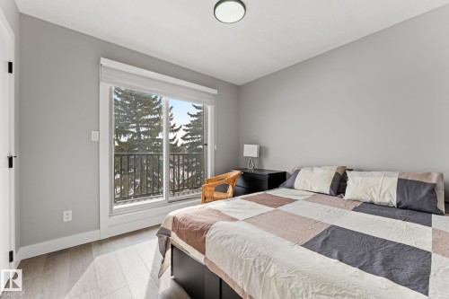 Bright room featuring wood-finish flooring, a full-lite exterior door with a black railing balcony, and a flush-mount ceiling light - 10673 161 Avenue, Edmonton, AB - Indoor Photo Showing Bedroom