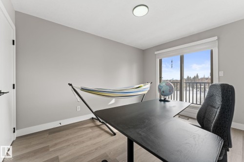 Room featuring light gray walls, wood-finish flooring, and a sliding glass door providing natural light - 10673 161 Avenue, Edmonton, AB - Indoor