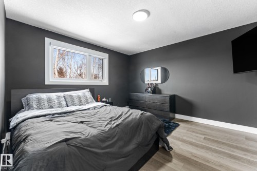 Bedroom featuring dark-toned walls, wood-finish flooring, a white trim baseboard, and a flush-mount ceiling light - 10673 161 Avenue, Edmonton, AB - Indoor Photo Showing Bedroom