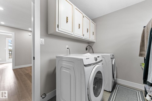 Dedicated laundry space featuring overhead white cabinetry with gold-tone hardware, providing storage solutions - 10673 161 Avenue, Edmonton, AB - Indoor Photo Showing Laundry Room