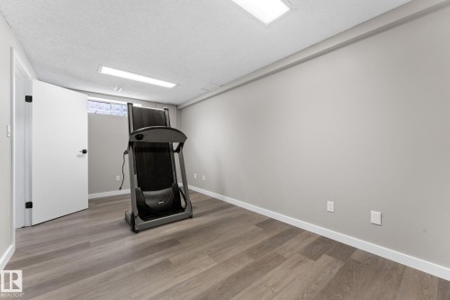 Spacious room featuring wood-finish flooring, light grey walls, and white baseboards - 10673 161 Avenue, Edmonton, AB - Indoor
