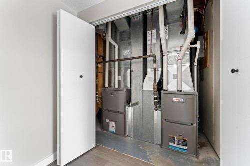 Dual HVAC units within a utility closet, featuring exposed ductwork and piping - 10673 161 Avenue, Edmonton, AB - Indoor Photo Showing Basement