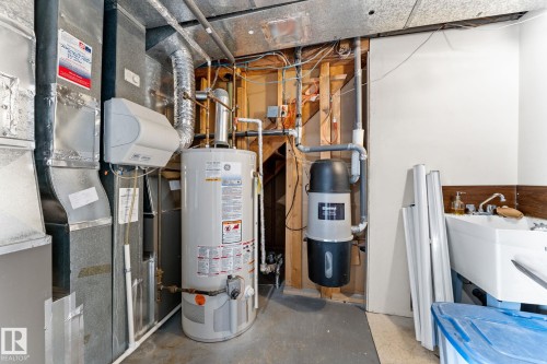 Utility area featuring a water heater, central humidifier, ductwork, central vacuum system, and a utility sink with a wood-finish backsplash - 10673 161 Avenue, Edmonton, AB - Indoor Photo Showing Basement
