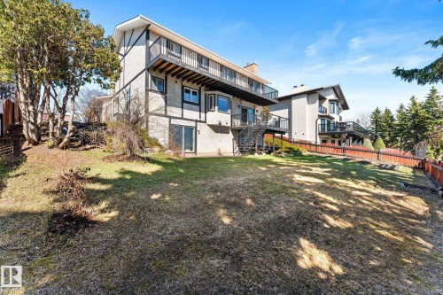 Sloping grass yard with mature trees and a multi-level residence featuring balconies and exterior stairs - 10673 161 Avenue, Edmonton, AB - Outdoor