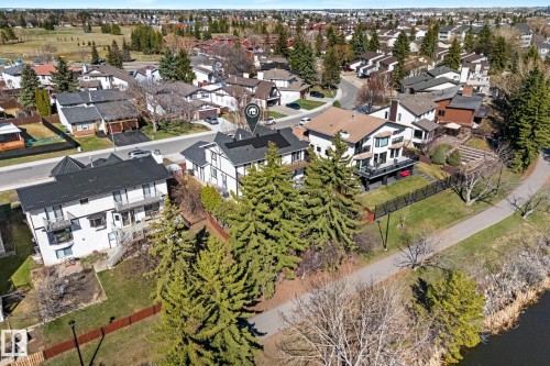 Aerial perspective showcasing a residential property with a dark roof and white facade, surrounded by mature evergreen trees - 10673 161 Avenue, Edmonton, AB - Outdoor With Body Of Water With View