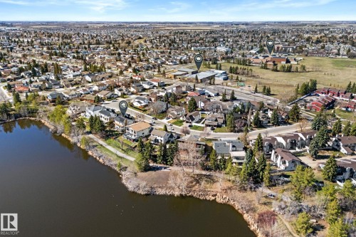 Lakeside property featuring multi-story residential architecture, mature perimeter trees, and a paved walking path - 10673 161 Avenue, Edmonton, AB - Outdoor With Body Of Water With View