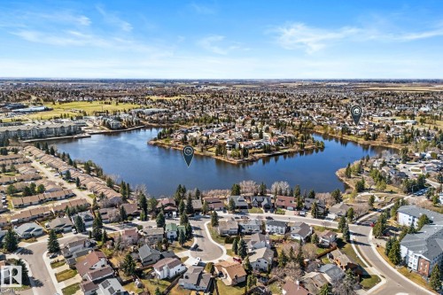 Aerial perspective showcasing a residential area with a prominent central lake, surrounding green spaces, and a mix of single-family homes and multi-story buildings - 10673 161 Avenue, Edmonton, AB - Outdoor With Body Of Water With View