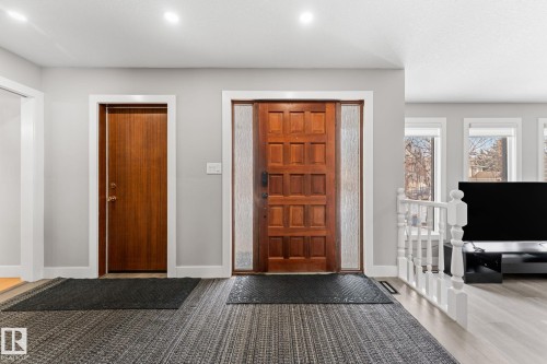 Front entry featuring a paneled wood door with frosted sidelights, wood-finish flooring, recessed lighting, and a white baluster railing - 10673 161 Avenue, Edmonton, AB - Indoor Photo Showing Other Room
