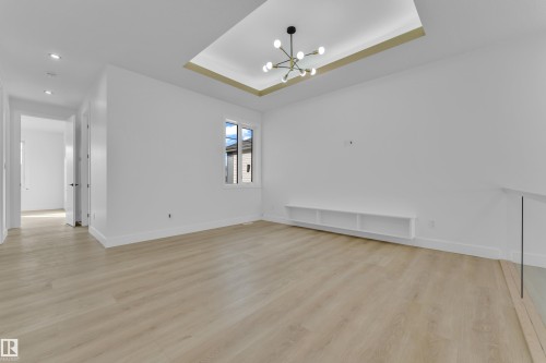 Spacious room featuring light wood-finish flooring, a contemporary chandelier, a single window, recessed lighting, and a built-in shelving unit - 449 Crystal Creek Link, Leduc, AB - Indoor Photo Showing Other Room