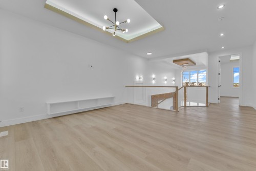 Open concept room featuring recessed and chandelier lighting, wood-finish flooring, a built-in shelf, and white walls - 449 Crystal Creek Link, Leduc, AB - Indoor Photo Showing Other Room