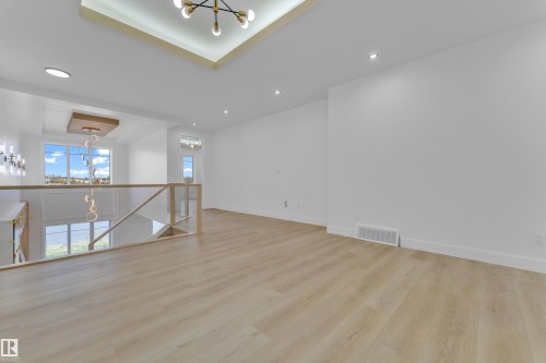 Open-concept upper level featuring light wood-finish flooring, recessed ceiling lighting, and a modern glass-paneled railing - 449 Crystal Creek Link, Leduc, AB - Indoor Photo Showing Other Room