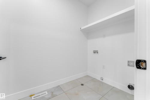 Utility room featuring light-toned tile flooring, clean white walls, and a built-in white shelf - 449 Crystal Creek Link, Leduc, AB - Indoor
