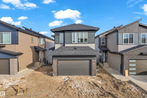 Contemporary two-story residence featuring a dark gray garage door, light gray siding, and a prominent front-facing window grouping - 449 Crystal Creek Link, Leduc, AB - Outdoor