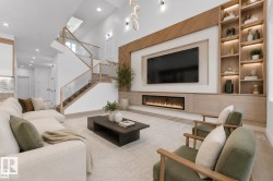 Great room featuring an integrated media wall with a linear electric fireplace, custom wood-finish built-in shelving with accent lighting, and a wood-finish staircase with glass panel railing - 