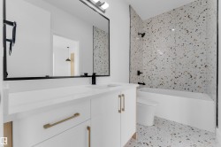 Bathroom featuring a white vanity with gold-tone hardware, a rectangular undermount sink, and a matte black faucet - 