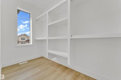 Walk-in closet featuring built-in shelving, hanging rods, wood-finish flooring, and a vertical window - 