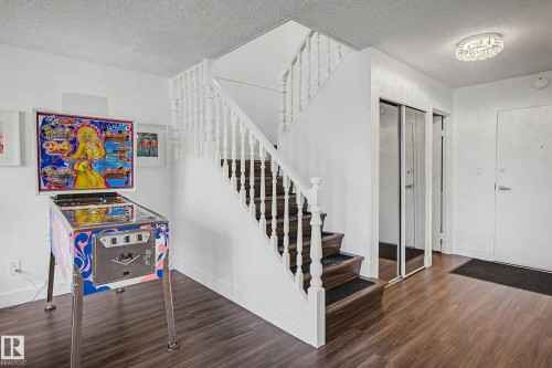 Staircase featuring white balusters and dark wood-finish treads with risers, complemented by rich wood-finish flooring - 1205 10045 118 Street, Edmonton, AB - Indoor Photo Showing Other Room