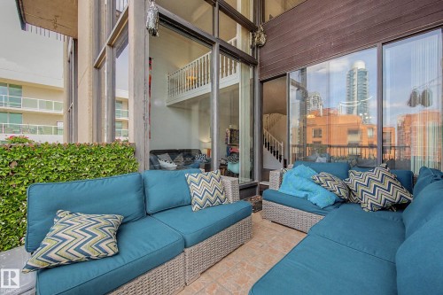 Expansive outdoor patio featuring tile flooring and a mature green hedge - 1205 10045 118 Street, Edmonton, AB - Outdoor With Balcony With Exterior