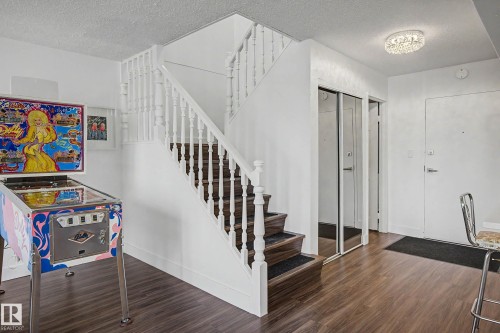 Staircase entry featuring wood-finish flooring, white balusters, mirrored closet doors, and recessed lighting - 1205 10045 118 Street, Edmonton, AB - Indoor Photo Showing Other Room