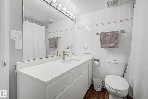 Bathroom featuring a single vanity with a white countertop, under-mount sink, and gold-finish faucet - 1205 10045 118 Street, Edmonton, AB - Indoor Photo Showing Bathroom