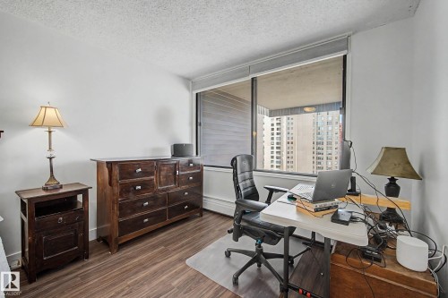 Spacious interior featuring wood-finish flooring, a large window, and light-colored walls - 1205 10045 118 Street, Edmonton, AB - Indoor Photo Showing Office