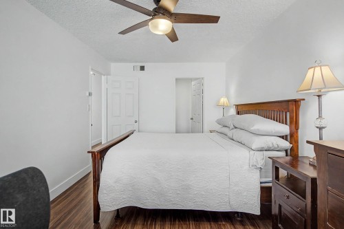 Bright bedroom featuring wood-finish flooring, a ceiling fan with integrated lighting, and white paneled doors - 1205 10045 118 Street, Edmonton, AB - Indoor Photo Showing Bedroom