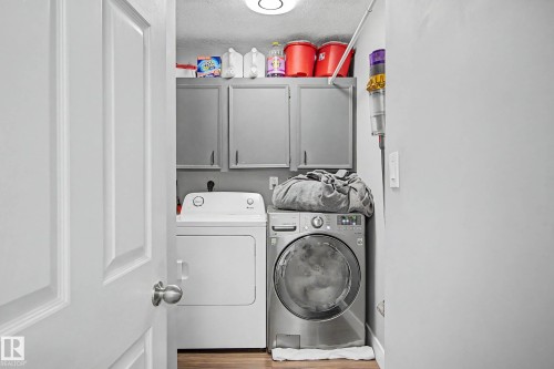Dedicated laundry area with built-in cabinetry and wood-finish flooring - 1205 10045 118 Street, Edmonton, AB - Indoor Photo Showing Laundry Room