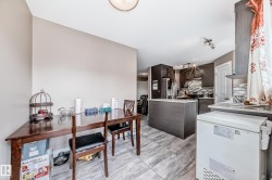 Open-concept kitchen and dining area featuring dark wood-finish cabinetry, a central island with a light-toned countertop, and patterned tile backsplash - 