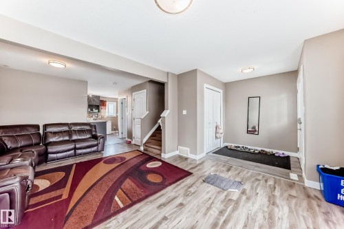 Spacious living area featuring wood-finish flooring, neutral wall tones, and recessed lighting - 1 12833 123 Street, Edmonton, AB - Indoor