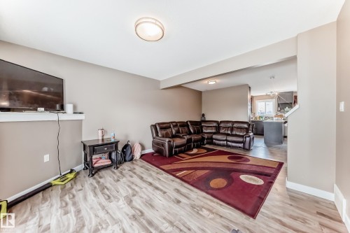 Spacious living area featuring wood-finish flooring, neutral wall paint, and recessed ceiling lighting - 1 12833 123 Street, Edmonton, AB - Indoor